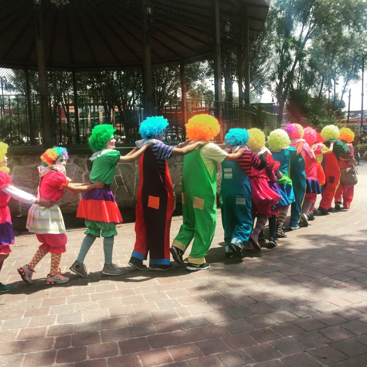 Sunday afternoon in the park and a conga line of clowns go by